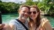 © Gabriel - A joyful couple taking a selfie by the serene waterside, surrounded by lush greenery
