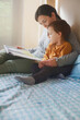© Oriol Roca  - Smiling mother reading storybook with toddler on bunk bed