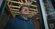 © Marco - Construction worker gazing up at open roof frame, wearing hard hat and glasses, with a thoughtful expression, focused on progress of building under construction