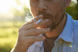 © New Africa - Man smoking cigarette outdoors on sunny day, closeup