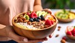 © patiwit - Nourishing delight, woman holding a bowl of fresh fruit and wholesome nuts
