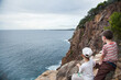 © Austockphoto - Two brothers sitting on the edge of a cliff looking over at the ocean