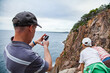 © Austockphoto - Man taking photos of his boys looking down cliff to the sea