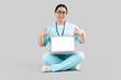 © Pixel-Shot - Female doctor pointing at blank laptop on light background