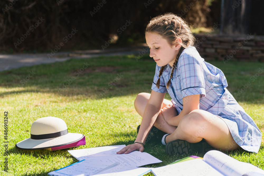 teen girl in school uniform doing homework outside on the grass Stock ...