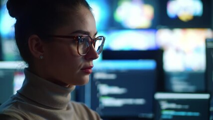 Focused programmer working late on coding project in modern tech workspace with multiple screens