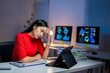 © Apichat - A woman in a red shirt is sitting at a desk with a computer monitor and a tablet