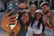 © bernardbodo - Happy tourists taking a photo of themselves and waving at camera in city center
