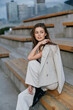 © SHOTPRIME STUDIO - woman sitting on urban stairs wearing beige suit jacket and pants with stylish black shoes in autumn fashion business portrait