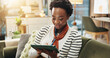 © peopleimages.com - Online, tablet and black woman in home for remote work, blog and ghost writer check report. Sofa, freelancer and technology with happy author reading email, research story and editing publication