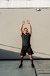 © Mdv Edwards - A middle-aged man performs jumping jacks outdoors against a concrete wall during a high-intensity workout session just outside the gym.