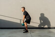 © Mdv Edwards - Fit middle-aged man outdoors holding kettlebell between legs, preparing for a swing exercise under late afternoon sunlight.