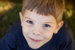 © Austockphoto - Portrait of happy young boy outdoors