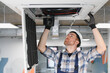 © Serhii - Hvac technician repairing air conditioner unit on ceiling