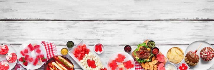 Fototapete - Canada Day patriotic food. Top view bottom border on a white wood banner background. Hot dogs, hamburgers and maple leaf red and white theme snacks. Copy space.