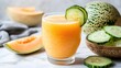 © Melll - Cantaloupe drink in a glass with cucumber, & cantaloupe wedges on marble