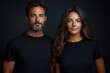 © Aleksandra - Portrait of a confident man and woman standing side by side against a dark background wearing black t-shirts with calm expressions