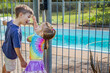 © Austockphoto - Brother and sister being silly outside pool gate