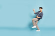 © comzeal - Happy Young Asian man smiling and pointing to empty copy space isolated on sky blue background, Full length composition