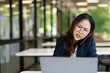 © maeching - Asian businesswoman working on financial market research using laptop and digital tablet, stressed about digital investment in office.