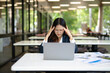 © maeching - Asian businesswoman working on financial market research using laptop and digital tablet, stressed about digital investment in office.