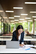 © maeching - Asian businesswoman working on financial market research using laptop and digital tablet, stressed about digital investment in office.