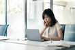 © Stock 4 You - Focused young Asian professional specialist businesswoman working on laptop pc sitting at desk in modern office. Middle-aged eastern business woman using computer technology app for work. Copy space