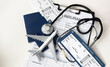 © Angelov - Medical tourism. Travel insurance application form, stethoscope, plane model and flight tickets on black wooden table, closeup