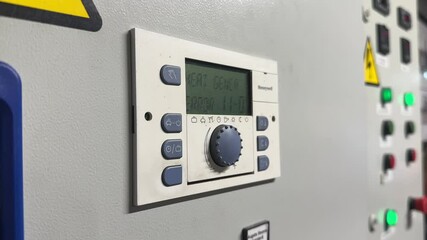 Close-up of a Honeywell industrial controller with display screen and control buttons on an electrical panel in a utility or control room.
