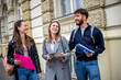 © Mediteraneo - Three Students Holding Books Laughing and Talking Together Outdoors