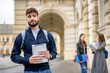 © Mediteraneo - Smiling Student Holding Tablet with Classmates in the Background..