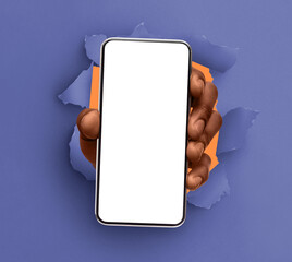 Mobile App, Great Offer. Closeup of black male hand holding smartphone with white empty screen showing device close to camera breaking through paper sheet. Gadget display with free copy space, mock up