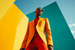 © Abeetha Prasad - A person in a yellow suit and red shirt posing against yellow and blue geometric shapes outdoors