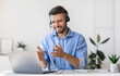 © Prostock-studio - Video Conference. Friendly man office employee in headset having web call on laptop at workplace, talking and gesturing at camera, copy space