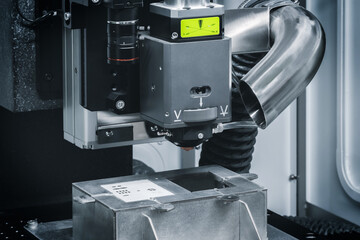 Poster - A machine with a green light on it. The machine is used to make things. The machine is silver and black