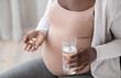 © Prostock-studio - Prenatal Vitamins And Supplements. Unrecognizable black pregnant woman taking pills capsules and glass of water, using medicaments for healthy pregnancy, cropped image, closeup