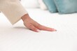 © New Africa - Woman touching soft mattress on bed indoors, closeup