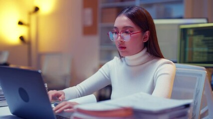 asian female programmer sits a dark tech workspace at night, fully focused on developing an online project. She writes HTML scripts and code for a modern website while contributing to automation work	