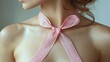 © Endri - Close-up of a woman’s neck and upper chest with a delicate pink lace ribbon tied in a bow, soft natural lighting highlighting smooth skin and subtle shadows