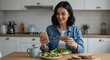 © rdkcho - Happy young woman using smartphone while enjoying healthy meal in modern kitchen