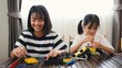 © FAMILY STOCK - Two Asian girls working together on robotics project at home. Promoting STEM education, teamwork, coding, and problem-solving through hands-on engineering and creative learning.
