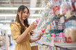 © Art_Photo - Young asian mother shopping milk bottles for newborn in supermarket, holding and comparing bpa-free baby feeding bottles for infant care, parenthood and baby product selection in retail store