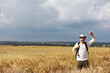 © alexkich - Tourist in a field of cereal plants. A man in a wheat field. Grain harvest.
