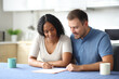 © Antonioguillem - Interracial couple signing lease contract at home