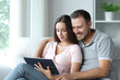 © Antonioguillem - Couple watching media on tablet sitting in a sofa