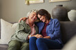 © Rido - Loving and happy mother embracing adult daughter on couch at home
