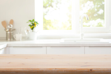 Wall Mural - old wooden table top for product montage on blur kitchen counter with utensils, sink and window inte