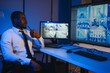 © Serhii - African-American security officer watching the screens talking on radio in control room