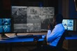 © Serhii - African-American security officer watching the screens talking on radio in control room