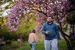 © Oleksii Yemelianov - Man Walking with Phone Under Cherry Blossom Trees